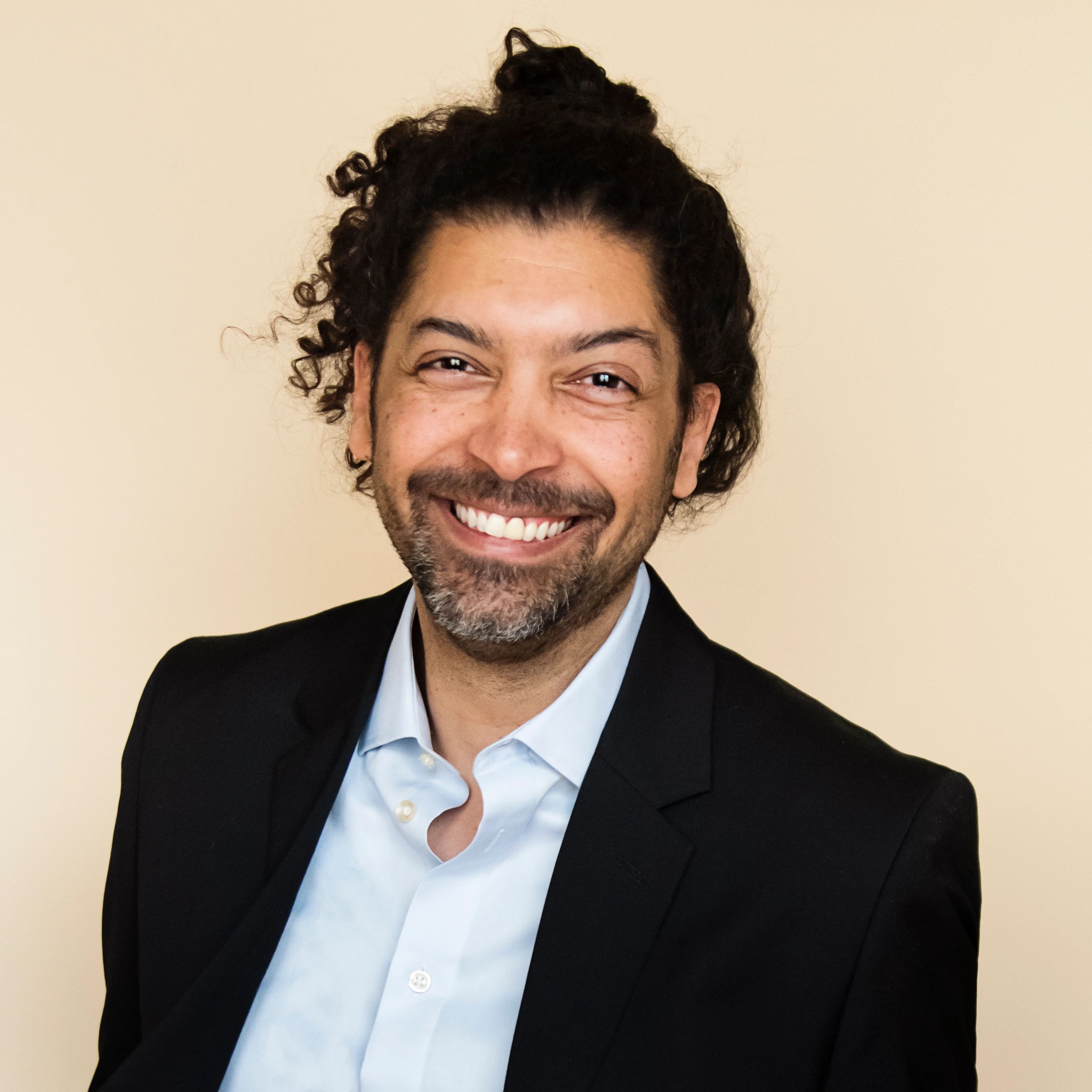 Professional headshot of a man in a suit on a beige background